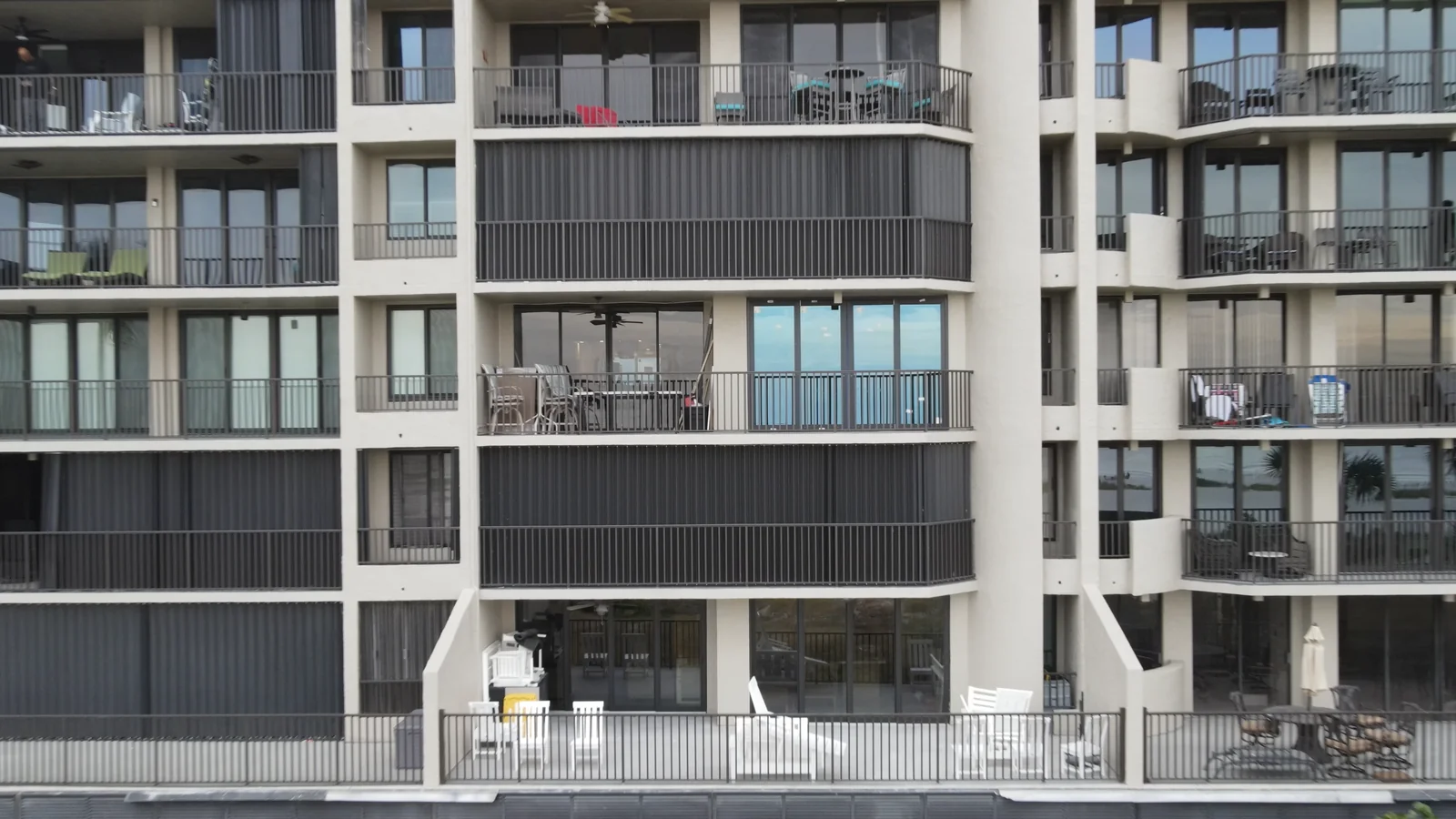 Condominium facade with glass sliding doors, windows and balcony railings.