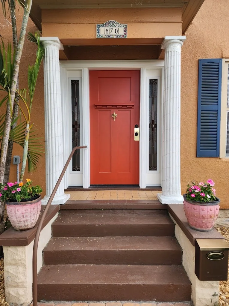Red front entry door with decorative glass, matching sidelights and white trim.