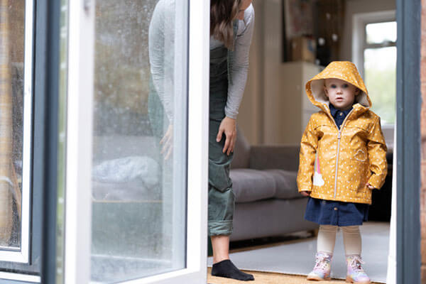 toddler standing with mom on the doorway